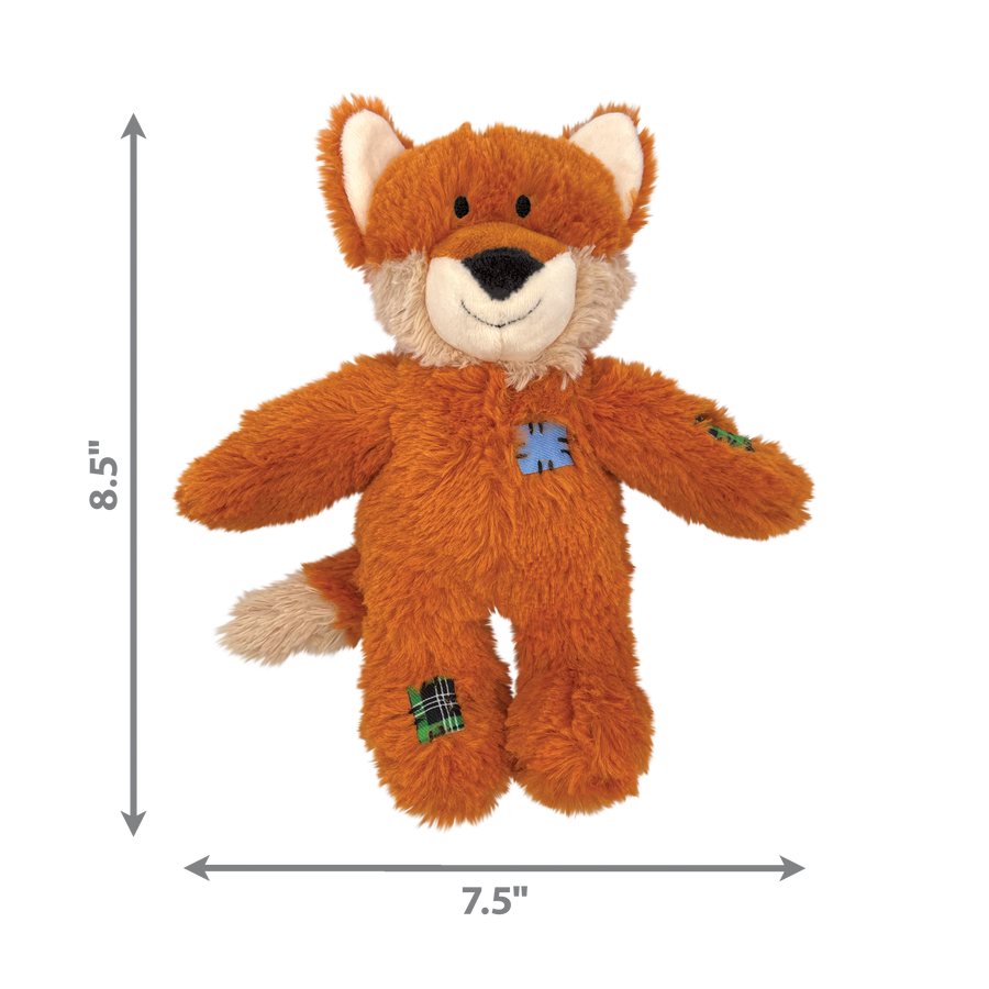 A KONG Wild Knots Fox Dog Toy, measuring 8.5 inches in height and 7.5 inches in width. The plush fox toy has an orange fur exterior with a white muzzle, inner ears, and tail tip. It features a smiling expression and stitched patch details on the body and limbs, giving it a rustic look. Designed for durability, the toy includes an internal knotted rope structure while maintaining a soft plush exterior for comfort during play and cuddles.