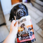 Black dog looking at Ultimates Jerky Sticks with Beef Dog Treats