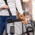 Bergan Booster Soft Pet Carrier, a woman is using the shoulder strap, with a small dog sitting inside the carrier. The dogs head is popped out of the carrier.