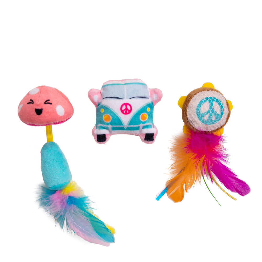 Three colorful cat toys with a playful, festival theme: a smiling pink mushroom with a blue stem and multicolored feather tail, a teal and pink cartoon van with a pink peace symbol on the front, and a small drum-like toy with a mesh surface, a blue peace symbol, and vibrant orange, pink, and purple feathers.