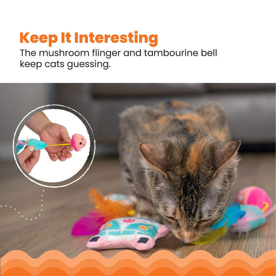 A cat plays with colorful toys, including a mushroom flinger and tambourine bell. Inset shows the mushroom toy being stretched. "Keep It Interesting – The mushroom flinger and tambourine bell keep cats guessing."
