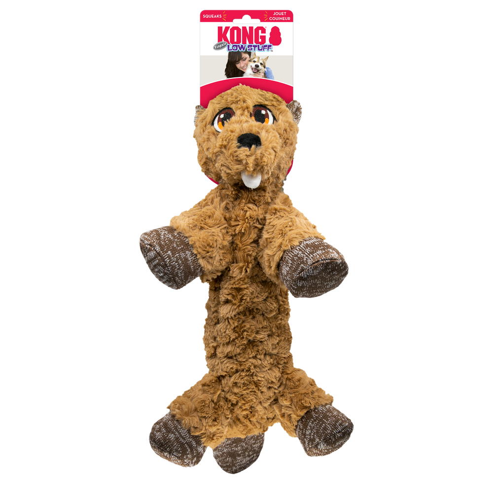 A KONG Low Stuff Flopzie Beaver Dog Toy, designed to resemble a plush beaver with brown, fluffy fur and minimal stuffing. The toy has a long, floppy body, soft brown paws with a textured fabric pattern, and an embroidered face with large, expressive eyes and two small white teeth. The packaging at the top features the red KONG logo, an image of a happy dog, and the words 'Low Stuff' in blue, indicating the toy's low-stuffing design.