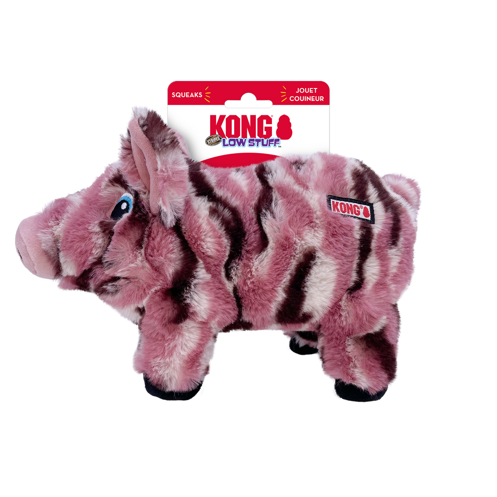 KONG Low Stuff Stripes Pig Dog Toy with a soft plush design, featuring a pink and dark brown striped pattern resembling a wild boar. The toy has blue embroidered eyes, black hooves, and a slightly textured snout. The KONG logo is sewn onto the side. The packaging at the top displays the KONG brand name, with 'Low Stuff' written underneath, indicating minimal stuffing inside. The tag also mentions that the toy squeaks.
