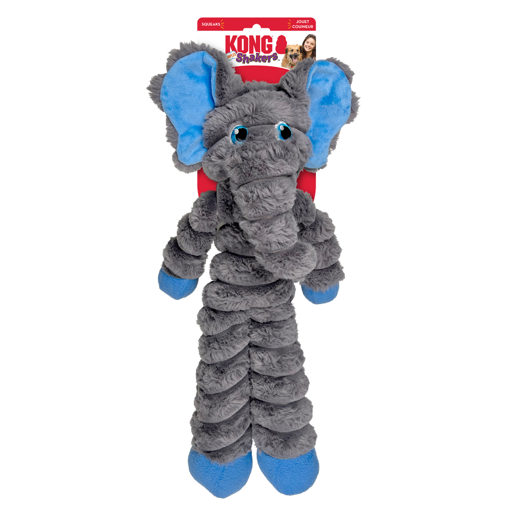 A KONG Shakers Crumples elephant plush dog toy in its original packaging. The toy is soft and gray with large floppy ears that have a bright blue inner lining. It features embroidered blue eyes, a long plush trunk, and a segmented crinkled body. The legs are long and floppy, ending in blue feet. The packaging is red and white, displaying the KONG logo, the word 'Shakers' in a playful red and pink font. The packaging also highlights that the toy squeaks.