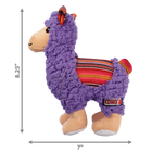 A KONG Sherps llama plush dog toy, measuring approximately 8.25 inches in height and 7 inches in width. The toy has a soft, purple fleece-like body with a beige muzzle and embroidered eyes. Its ears feature a colorful woven fabric with red, orange, and yellow stripes, which matches the saddle-like fabric on its back. The llama stands on beige plush legs with white hooves, and it has a small, fluffy tail. Measurement arrows along the sides indicate the toy’s dimensions.