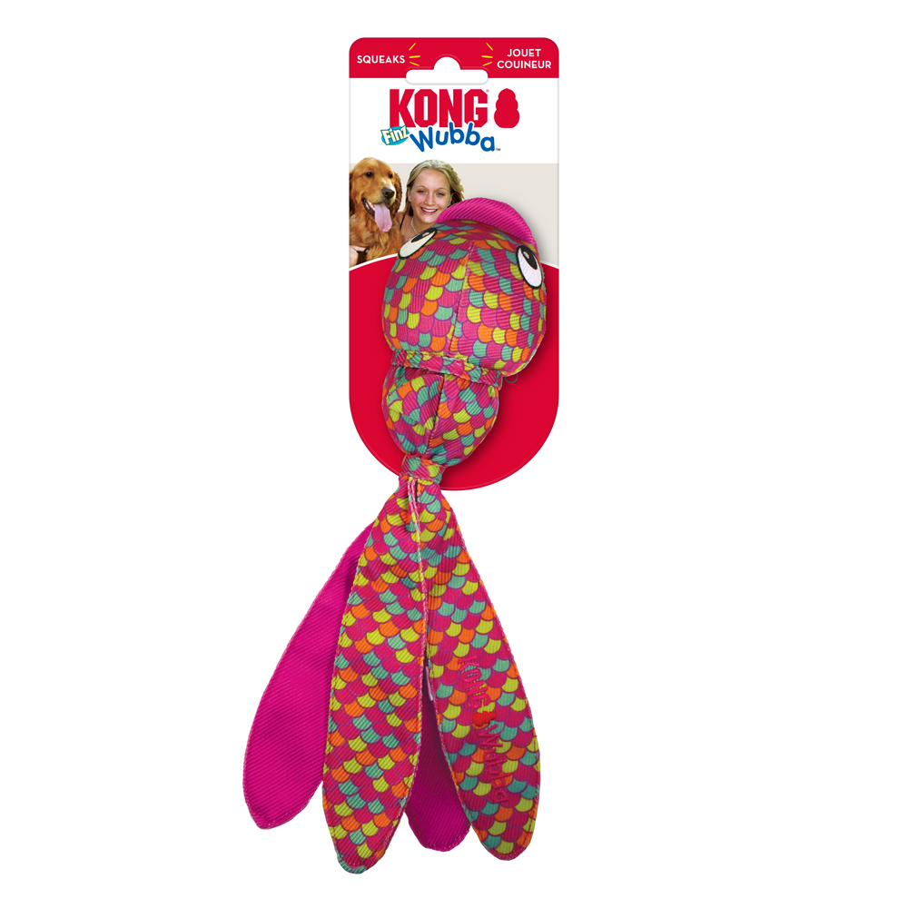 KONG Wubba Finz Pink Dog Toy in its original packaging. The toy resembles a fish with a round, bulbous head covered in a colorful scale pattern featuring shades of pink, red, yellow, green, and blue. It has large cartoonish eyes and a smaller ball-shaped section beneath the head. The long, fabric tentacle-like tails extend from the bottom, designed for interactive tossing and shaking. The packaging includes the KONG logo.