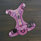 Wilderdog Lilac dog harness laid flat on dark wood surface, showing light purple mesh body, multicolor woven reflective strip, Wilderdog logo patch, quick-release buckles, and D-ring.