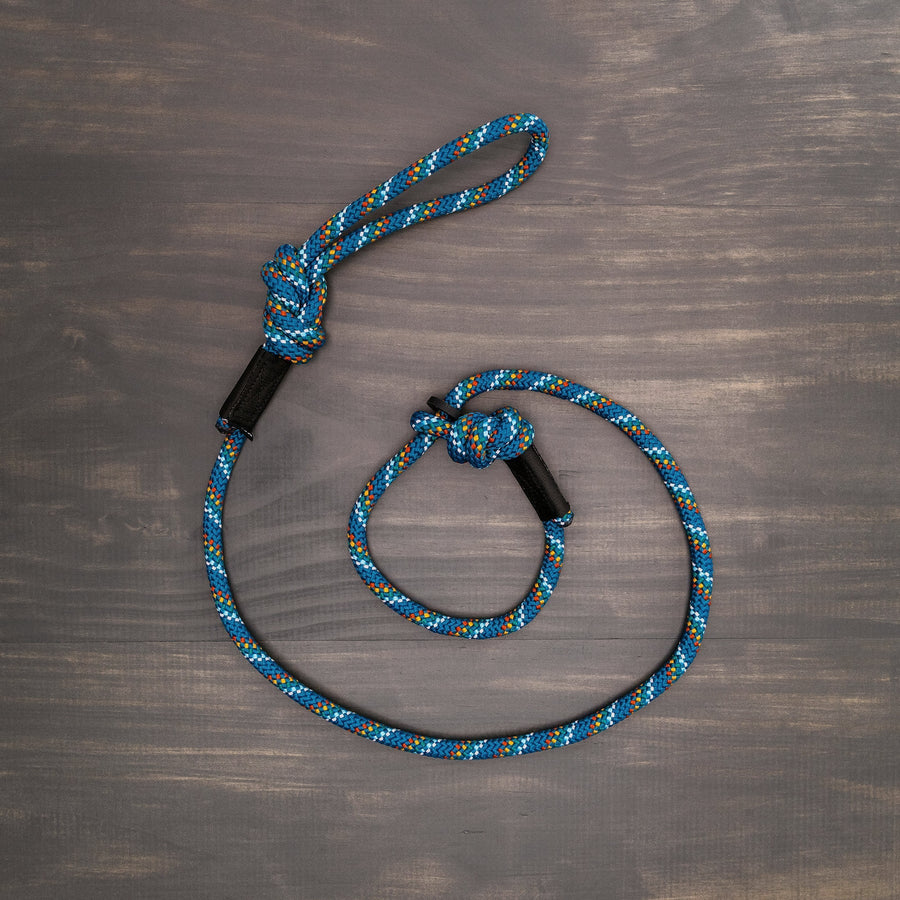 Wilderdog Reflective Slip Leash in Pacific Blue colorway laid flat on a wooden surface, showing the rope construction, adjustable slip loop, and knotted handle