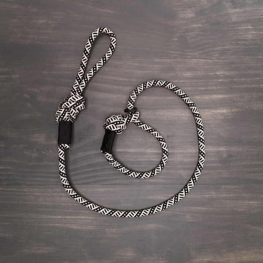Wilderdog Slip Leash in black and white geometric pattern laid flat on a wooden surface, showing the rope construction, adjustable slip loop, and knotted handle.