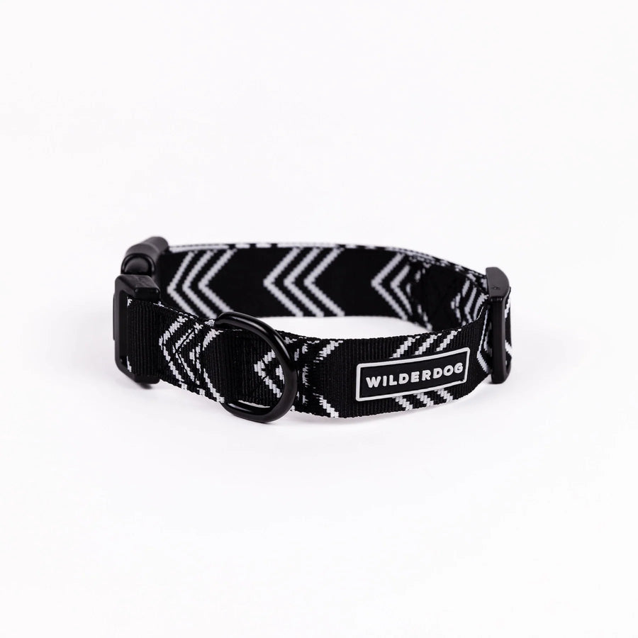 Wilderdog Orca ultralight dog collar on white background, showing black webbing with white chevron arrow pattern, black quick-release buckle, D-ring, and Wilderdog logo patch.