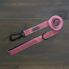 Wilderdog Ultralight Dog Leash in Lilac laid flat on dark wood surface, pink and orange speckled woven webbing with black Wilderdog carabiner clip, D-ring, and branded label.