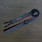 Wilderdog Ultralight Dog Leash in Marina colorway laid flat on dark wood surface, navy blue webbing with multicolor geometric pattern, black Wilderdog carabiner clip, D-ring, and branded label.